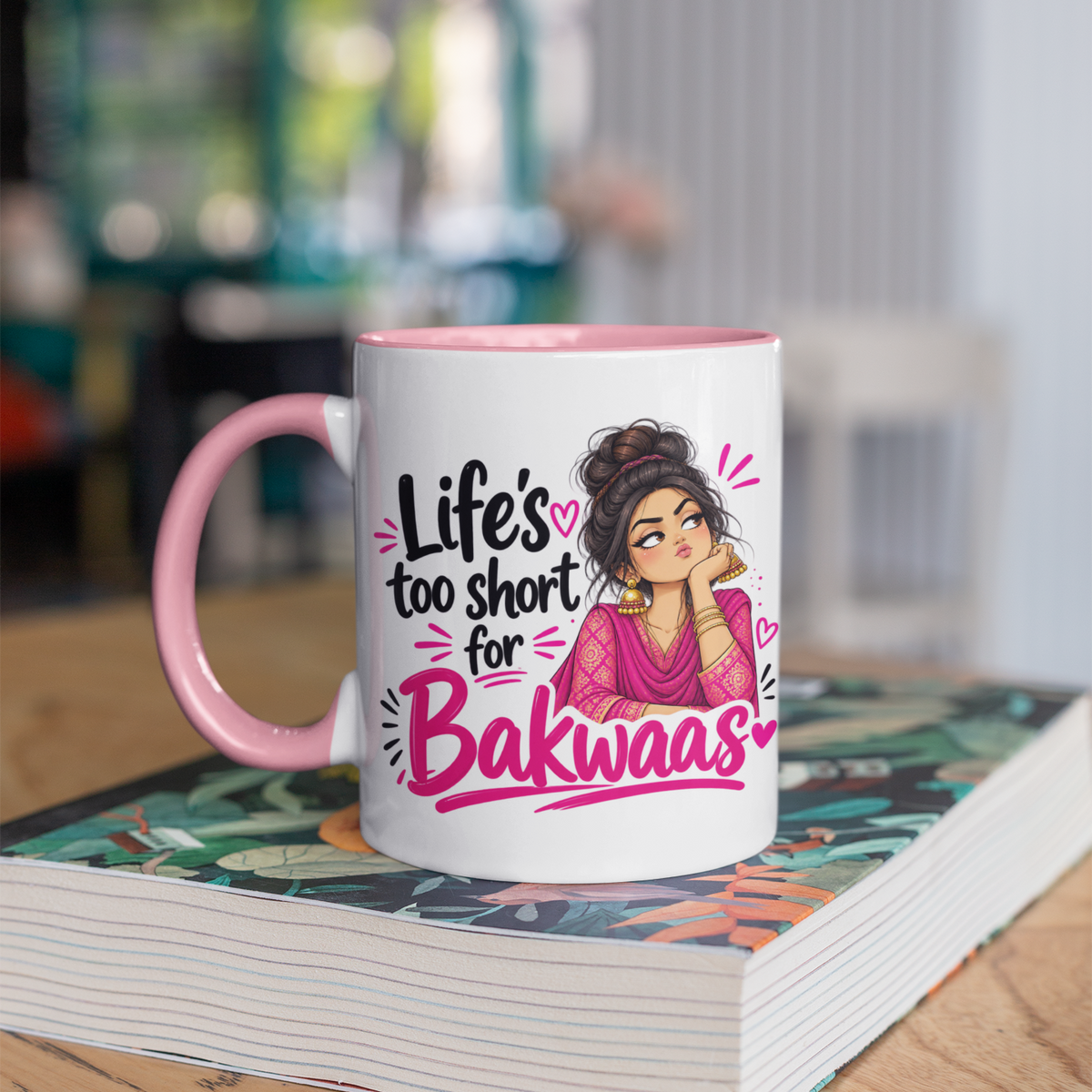 Pink mug with an illustrated woman in a pink outfit and messy bun, giving side-eye beside the words “Life’s too short for Bakwaas” in black and pink lettering