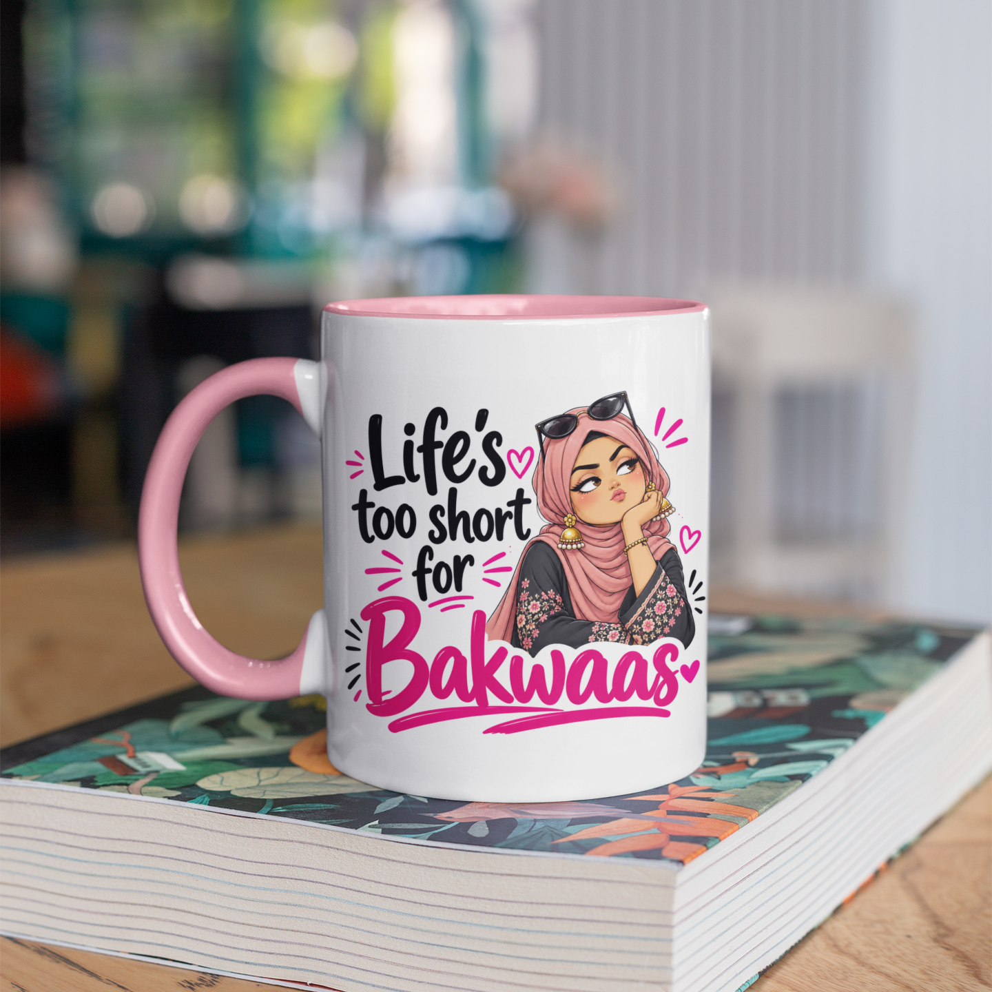 Pink mug with an illustrated woman in a pink hijab, sunglasses on her head and the words “Life’s too short for Bakwaas” in black and pink lettering